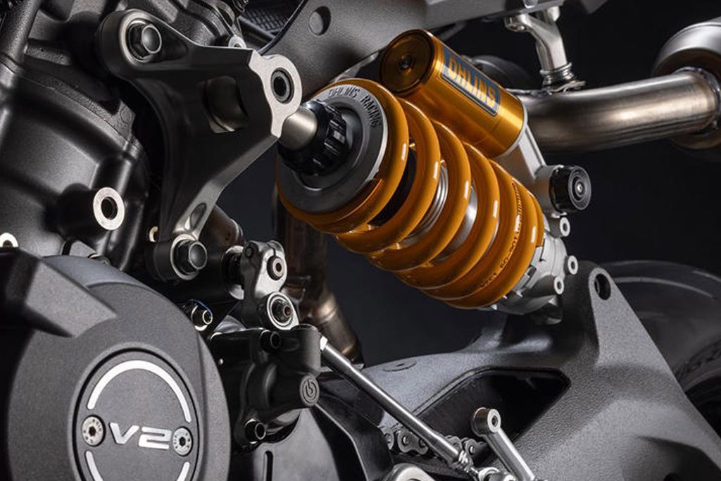 Suspensi belakang Öhlins pada Ducati Panigale V2 Special Edition MM93 menggunakan dudukan atas yang terhubung ke kepala silinder mesin V2. Konstruksi ini menjadi bagian dari desain motor yang mengutamakan efisiensi rangka, bobot ringan, serta performa pengendalian. Foto: Ducati/GridOto.com
